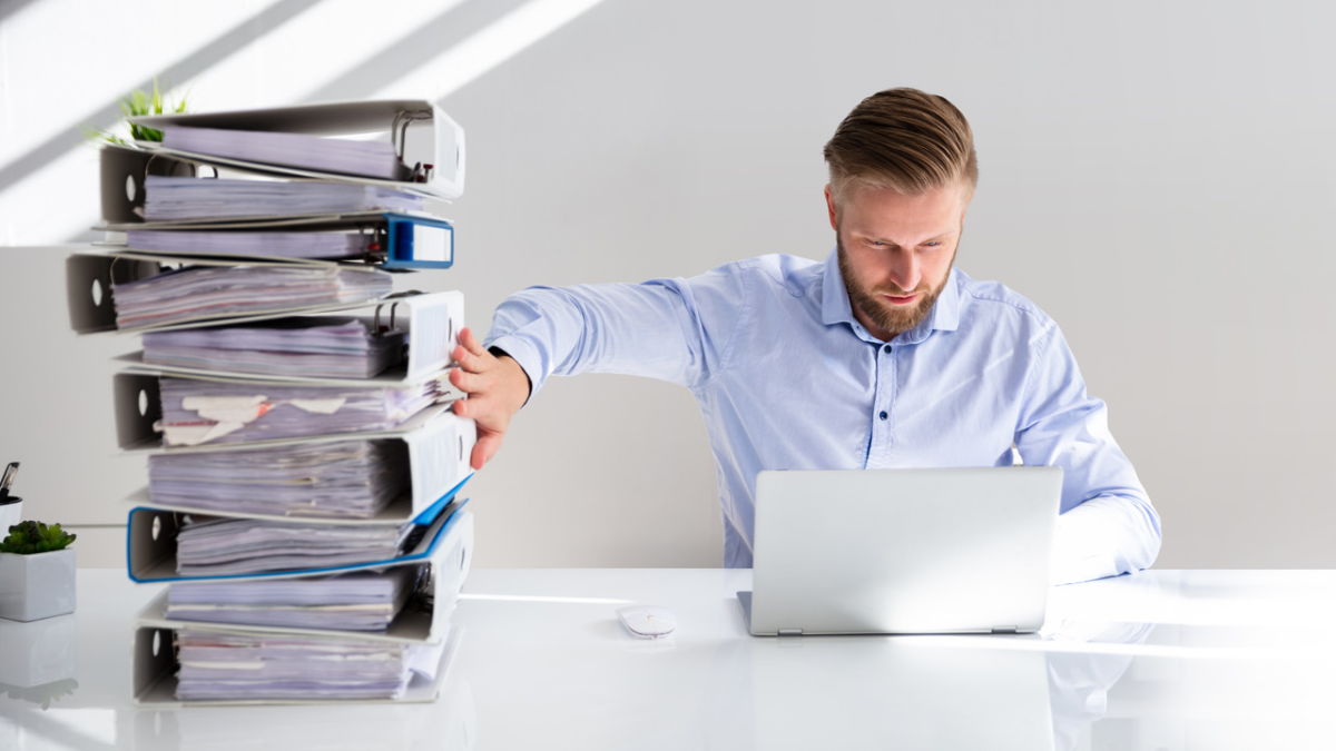 Mann schiebt Ordner weg weil er jetzt die Buchhaltung digital erledigen kann