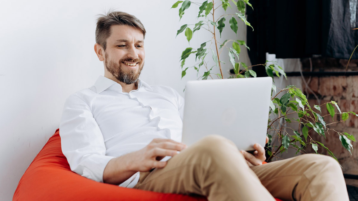 Mann arbeitet zufrieden im Sesseln mit Laptop